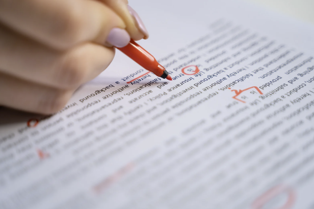 Woman editing a document with a red pen.