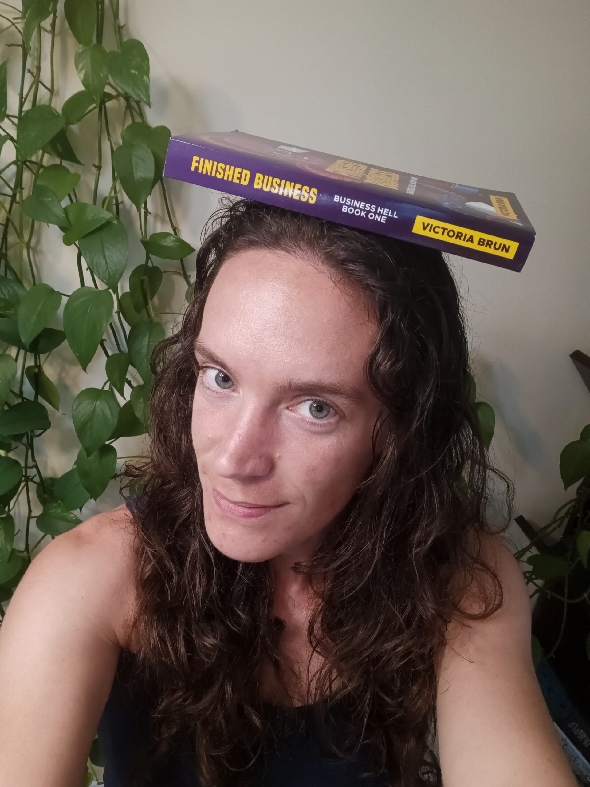 Headshot of Victoria wearing the book Finished Business as a hat.